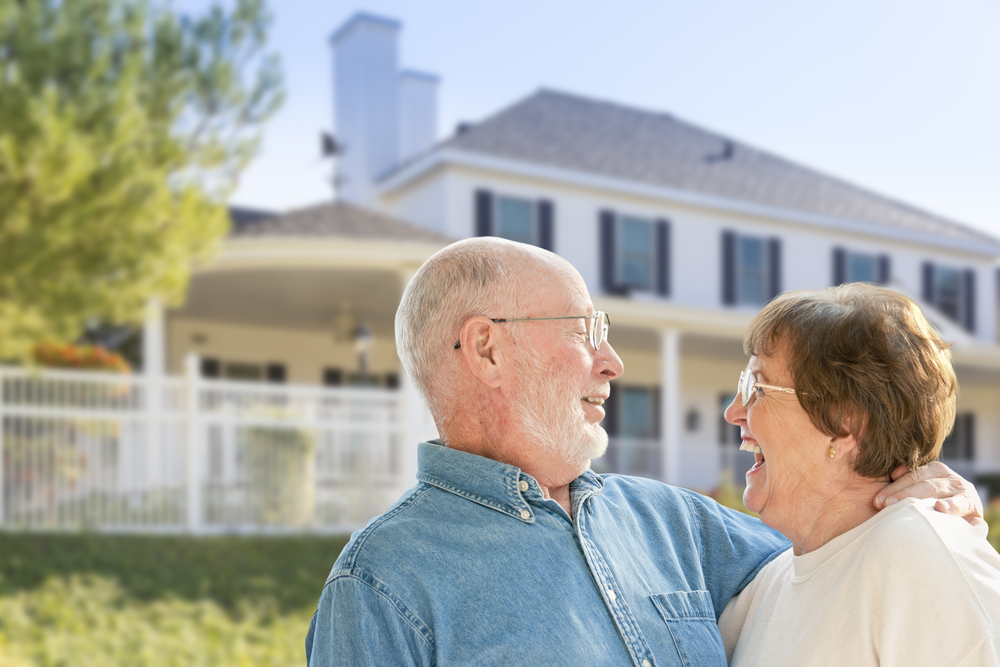 Happy seniors couple in front of their new home