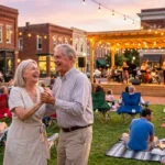 An active retired couple dancing at an outdoor community concert in a charming town square during a golden sunset.