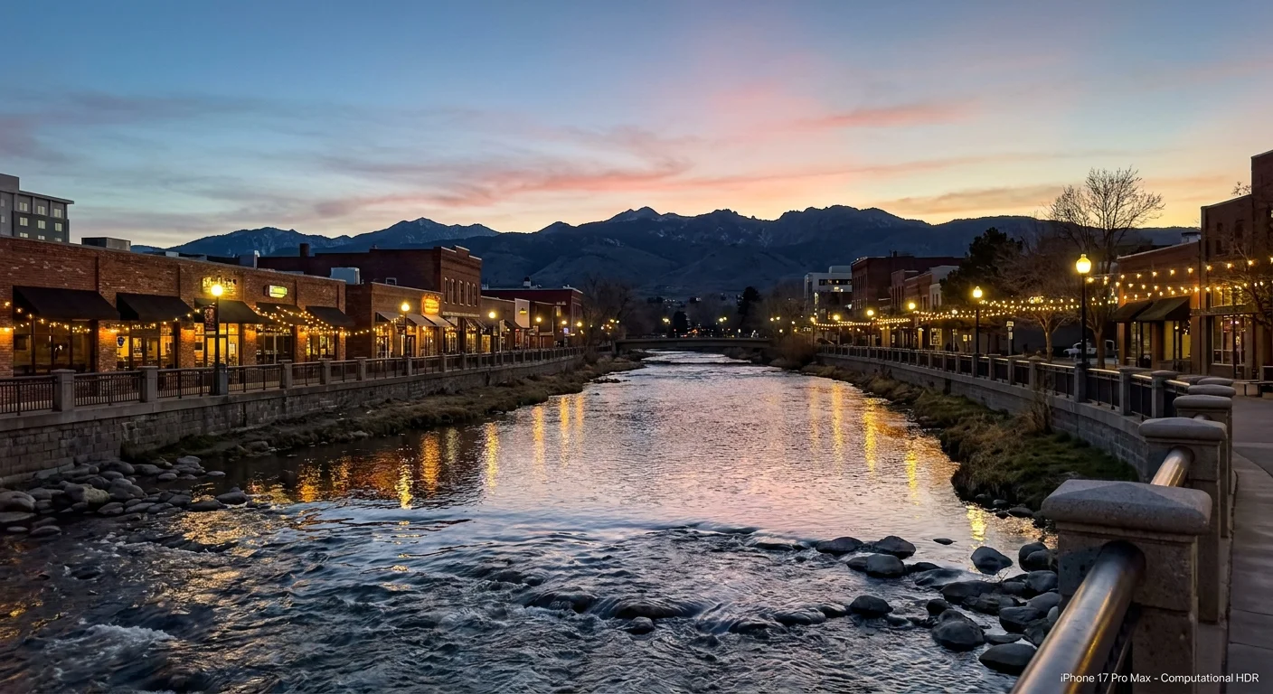 The Truckee River flowing through downtown Reno at sunset with mountain silhouettes in the distance.