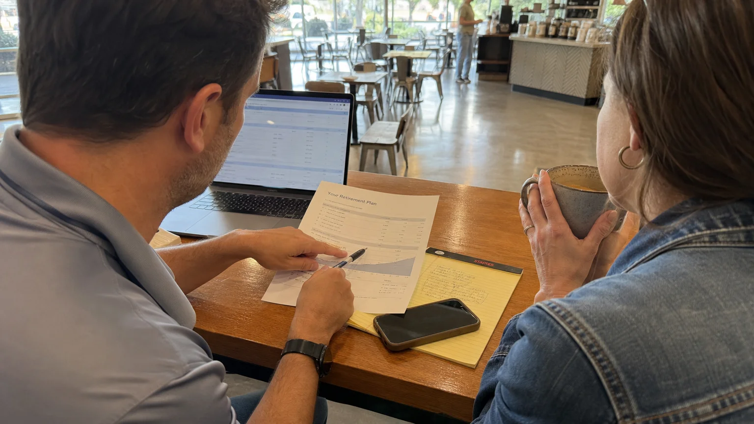 A candid photo of a casual meeting between a person and a financial advisor at a sunlit cafe.