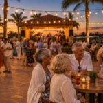 Older adults dancing and sitting at tables in an outdoor courtyard with string lights during an evening concert.