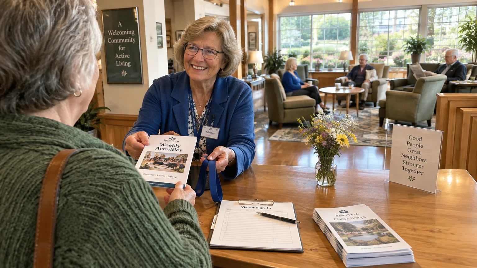 A smiling woman at a senior center reception desk hands an activities brochure to a visitor seated across from her.